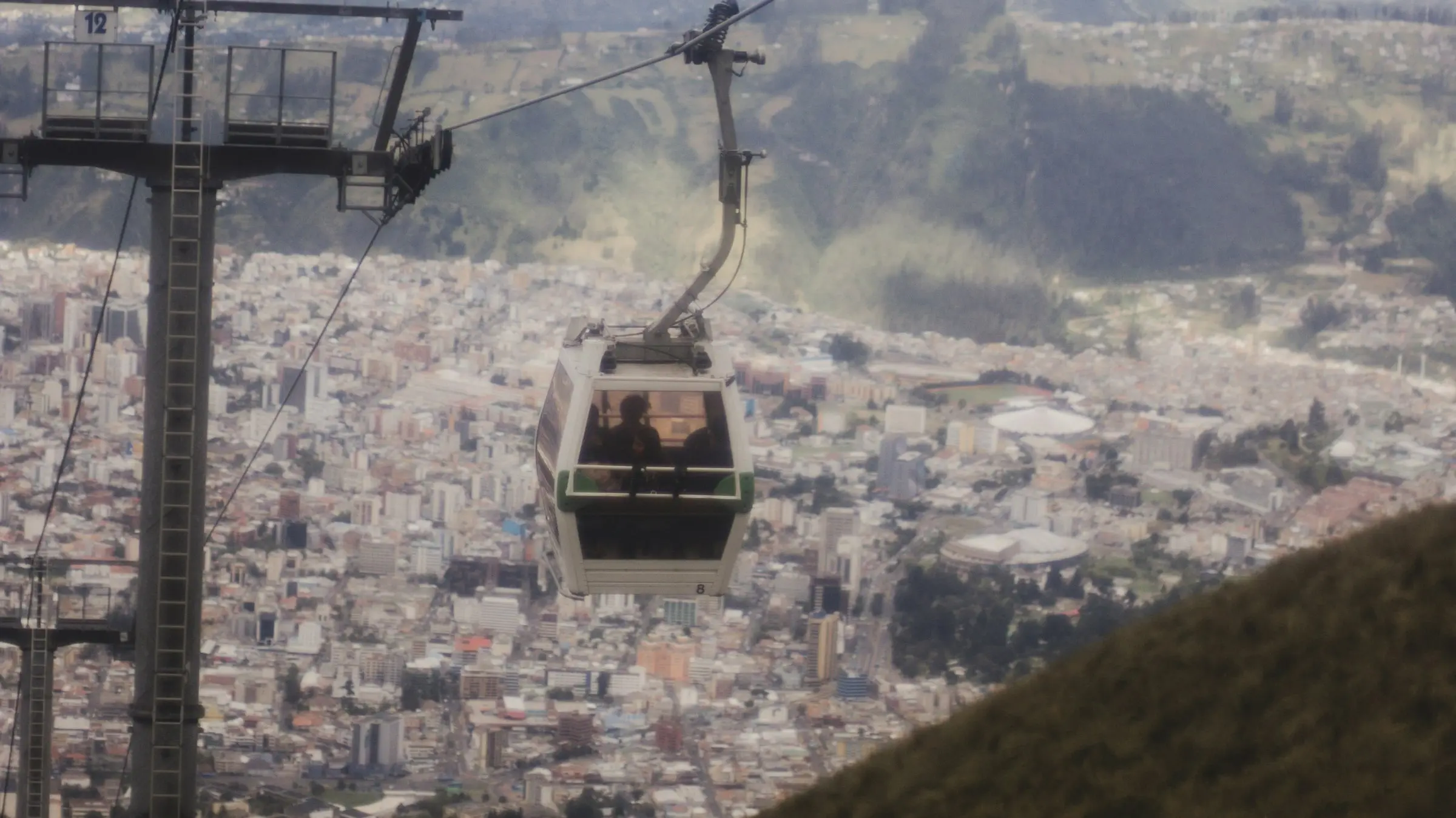 A TelefériQo cable car climbing above Quito, with the city spread out below and the Andes behind
